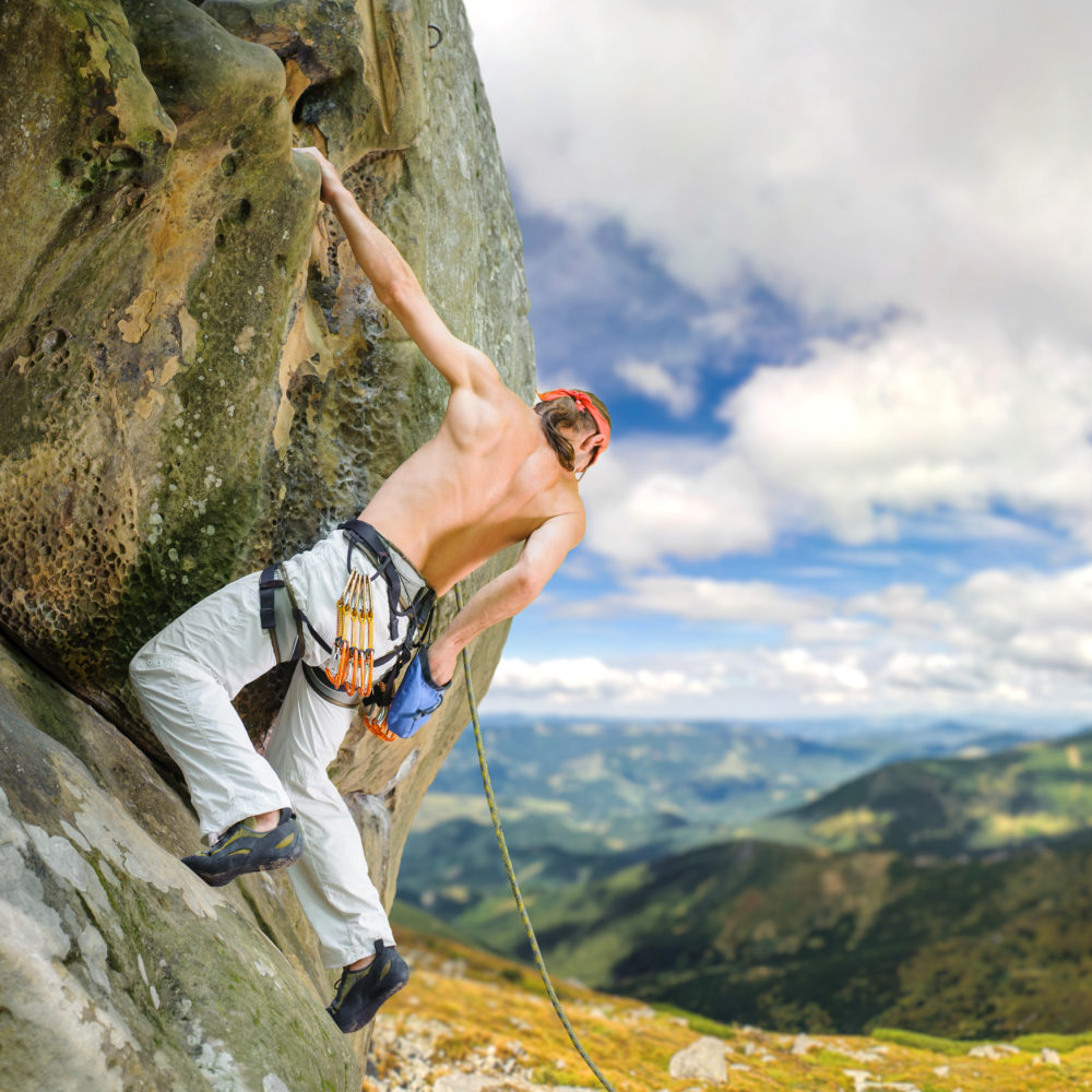 male-rock-climber-climbing-with-rope-on-a-rocky-wall-e1695355018602.jpg