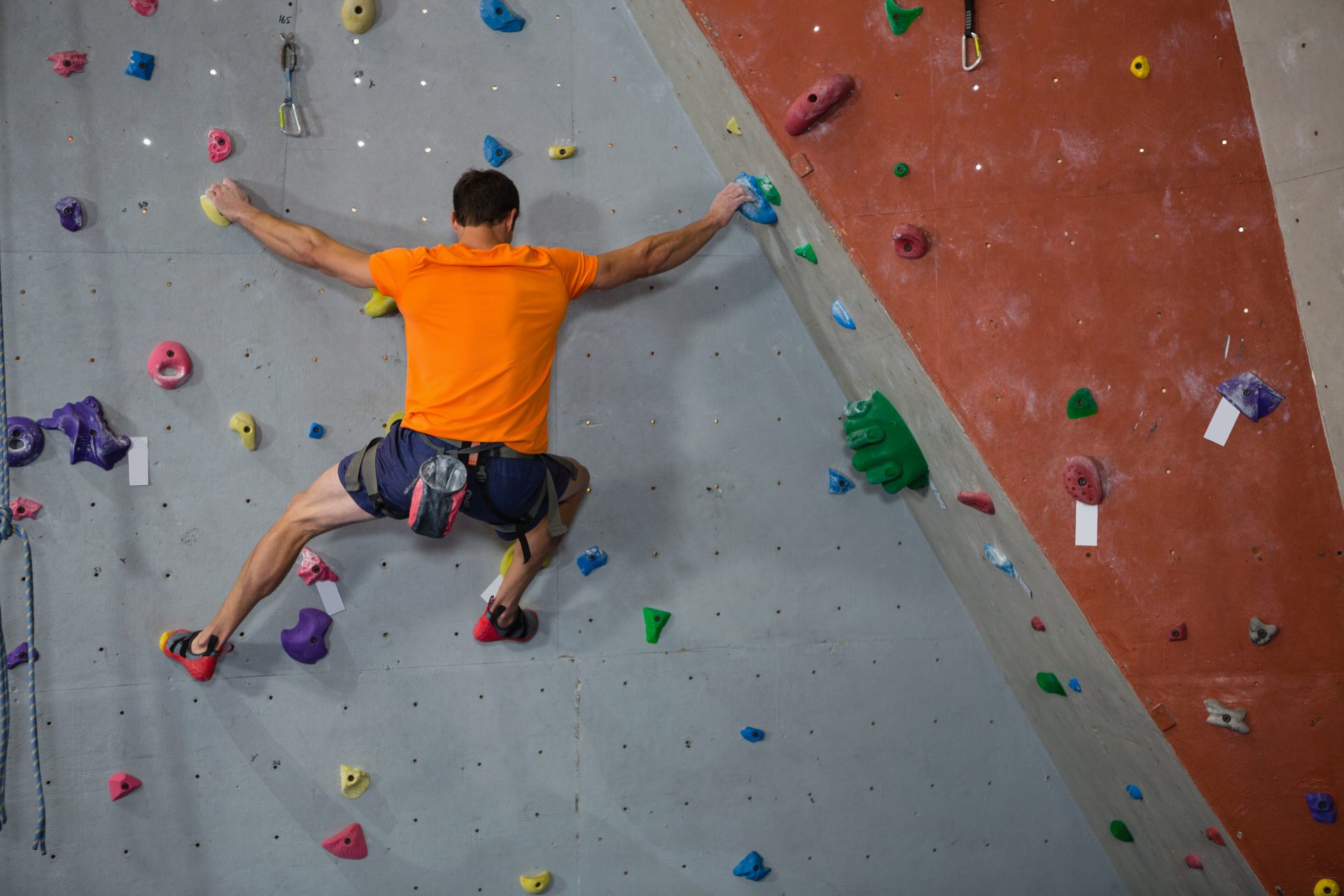 rear-view-of-athlete-rock-climbing-in-health-club-e1695696569297.jpg